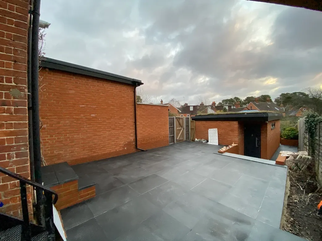 A brick building with a black roof next to a brick wall.
